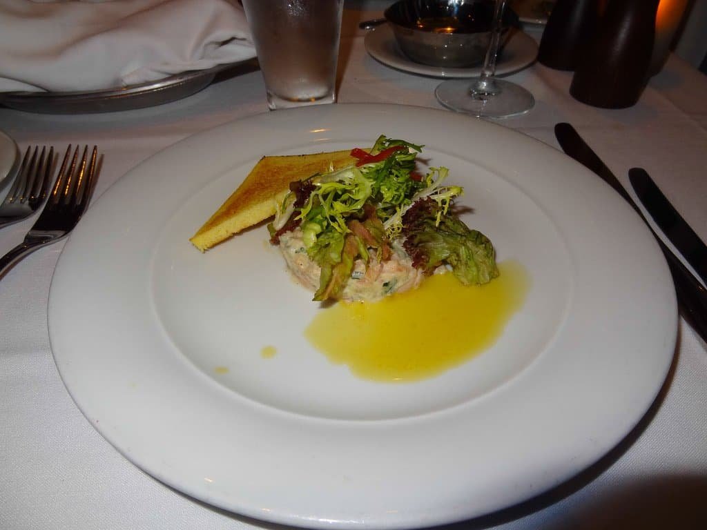 Seafood dish on a cruise ship with salad and lemon wedge.