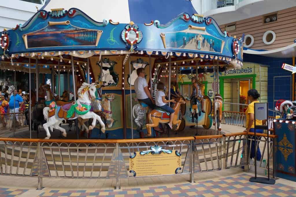 Carousel with children riding on colorful horses onboard cruise ship.