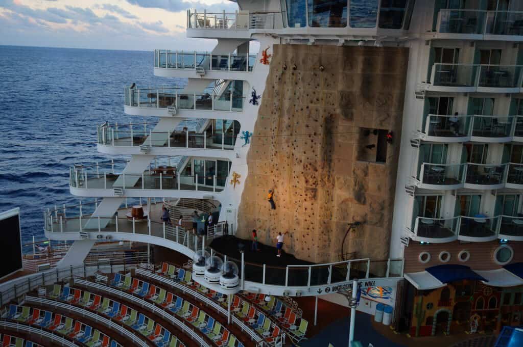 Rock climbing wall on cruise ship deck with passengers enjoying the activity.