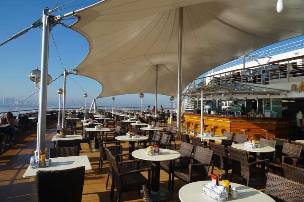 Outdoor cruise ship dining under shade sails.