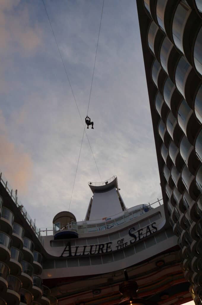 Allure of the Seas cruise ship with zip line and modern architecture.