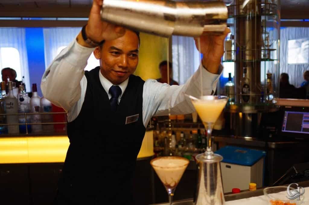 Bartender mixing drinks with shaker at Celebrity Silhouette cruise ship bar, creating cocktails for guests.