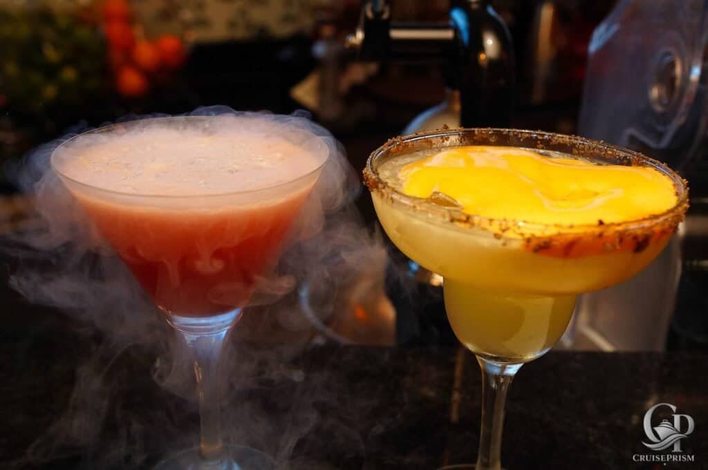 A vibrant pink and yellow cocktail with dry ice smoke, served in elegant glasses, perfect for cruise.