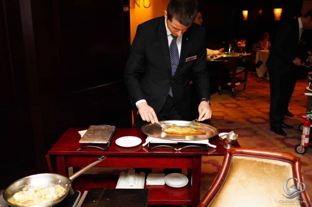 Celebrity silhouette Cruise ship waiter preparing Dover Sole dish in elegant restaurant setting.