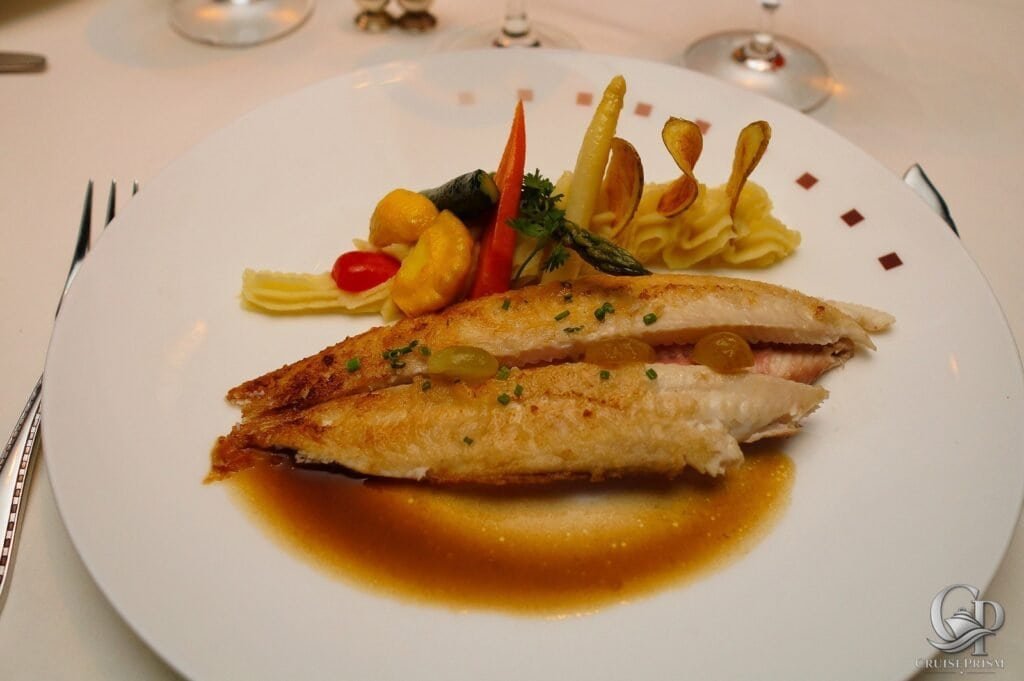Gourmet seafood presentation featuring a perfectly cooked Dover sole fillet with vibrant vegetables aboard Celebrity Silhouette.