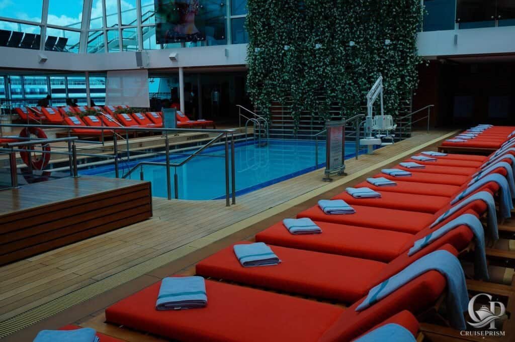 Celebrity Silhouette Solarium pool with orange lounge chairs and neatly folded towels.