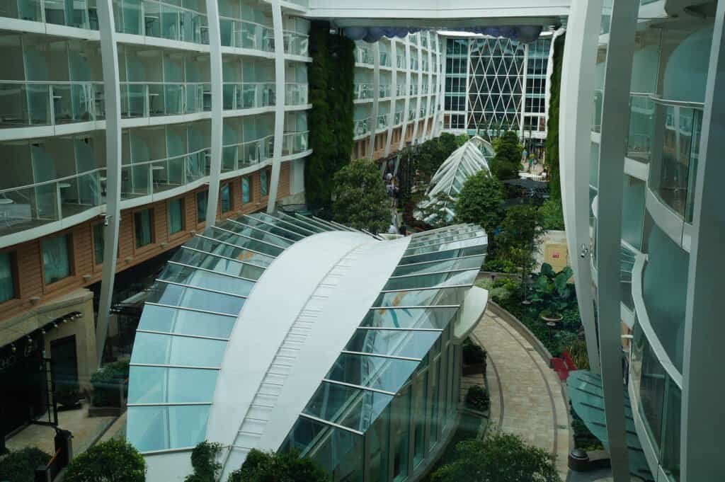 Luxury cruise ship interior with glass walkways and lush greenery.