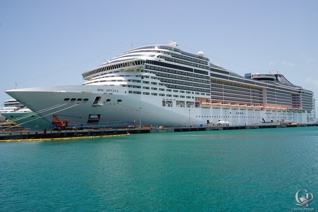Luxury cruise ship docked at port with multiple decks and modern amenities.