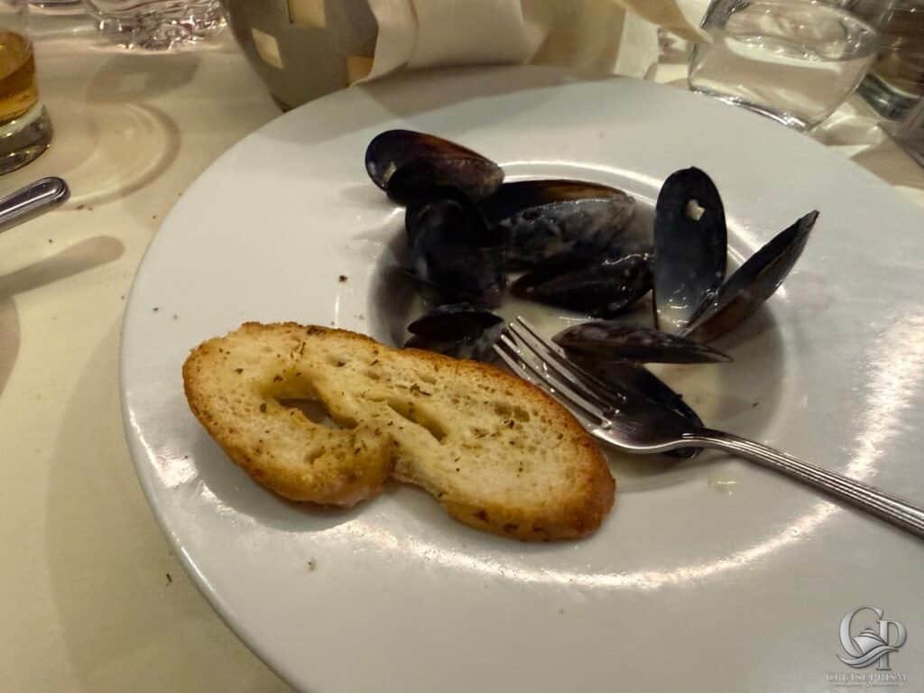 Seafood dish featuring fresh mussels served with toasted bread on a white plate.