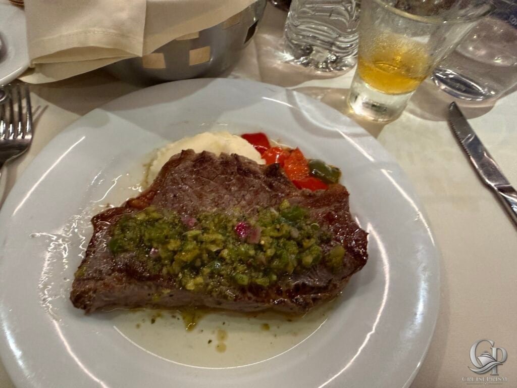 Juicy steak topped with green sauce served with mashed potatoes on a white plate.
