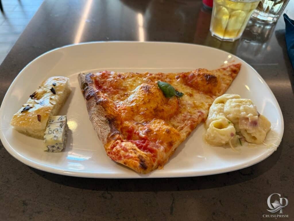Margherita pizza slice with fresh basil, cheese, and tomato sauce on a white plate.