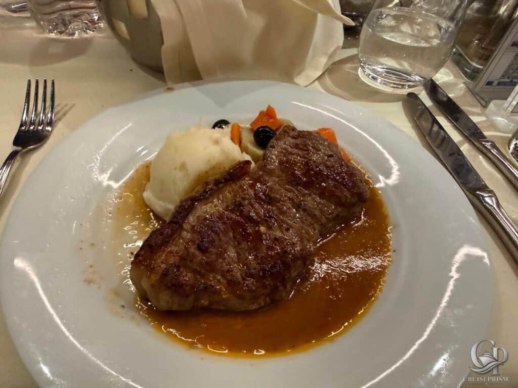 Juicy beef steak served with mashed potatoes and mixed vegetables on a white plate.