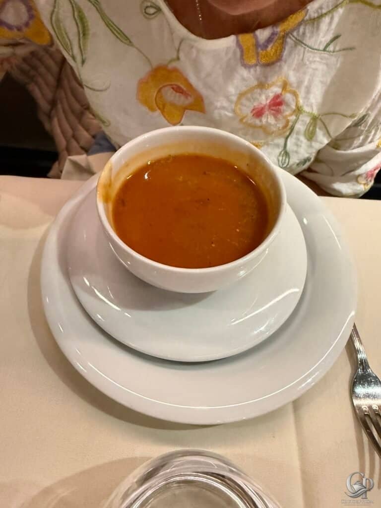 Delicious bowl of spicy soup served in a white cup on a saucer.