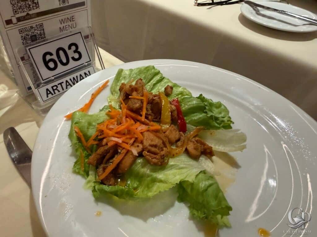 Fresh lettuce wrap filled with seasoned meat and vegetables, served on a white plate.