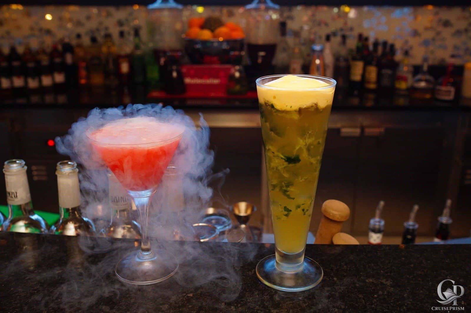 Vibrant cocktail with dry ice smoke at a bar setting.
